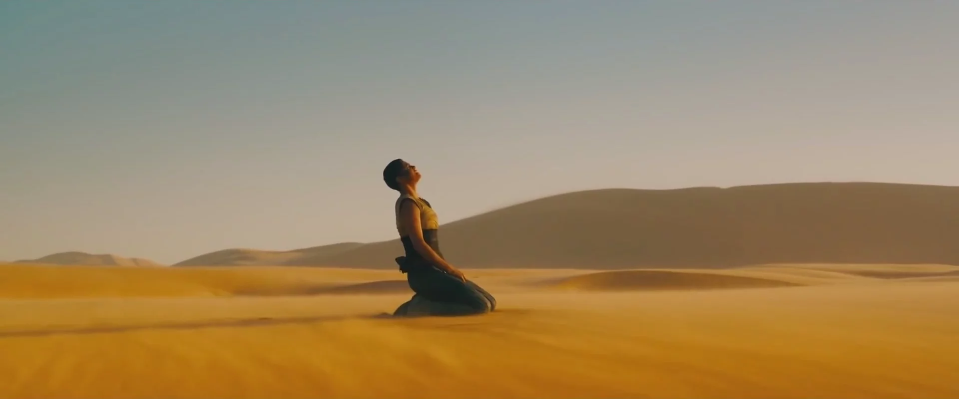woman in misery kneeling down in desert looking up at the sky