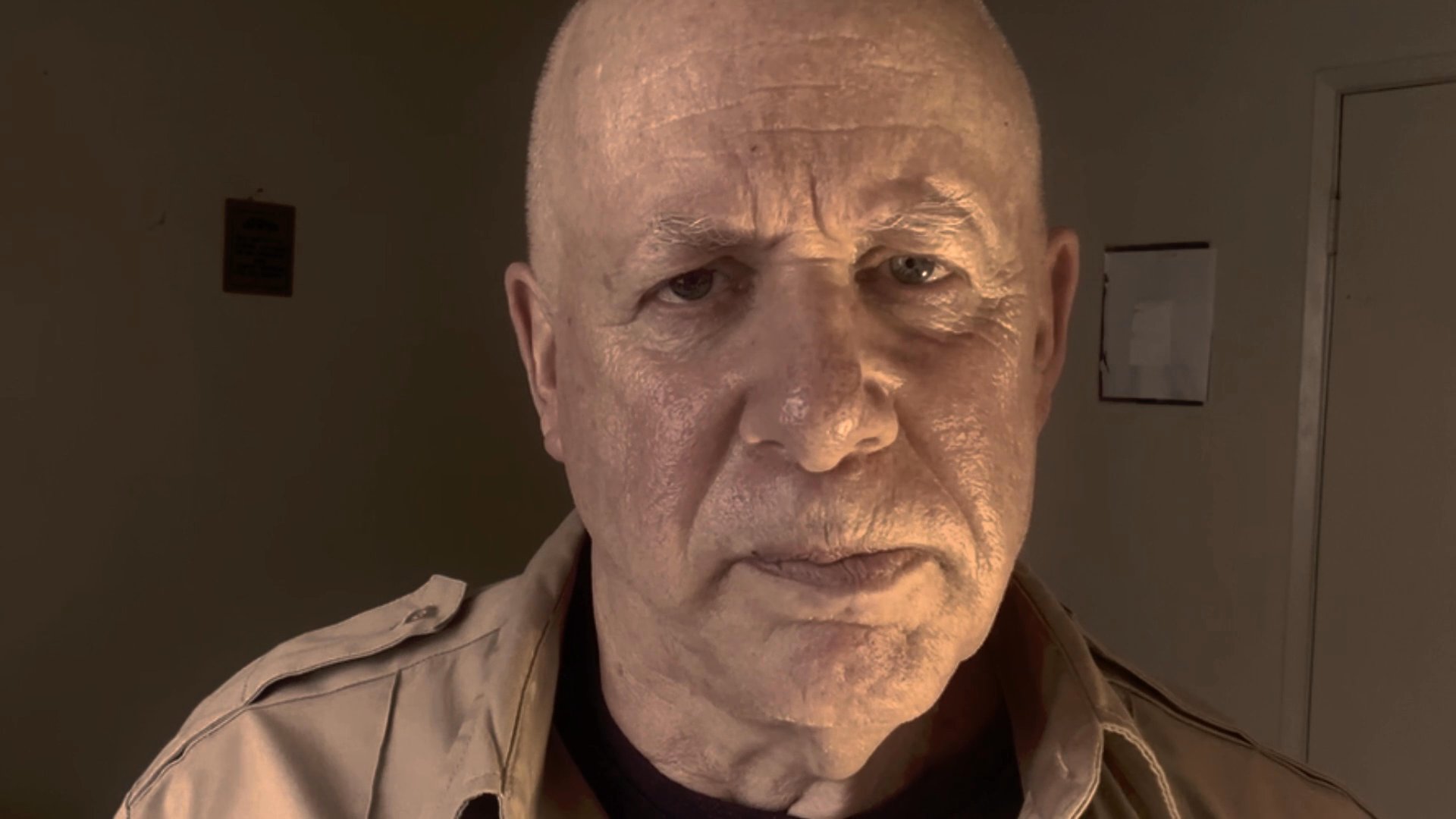 An older man speaks directly to the camera, delivering a focused message in an indoor setting. His expression conveys intentionality and seriousness throughout the presentation.