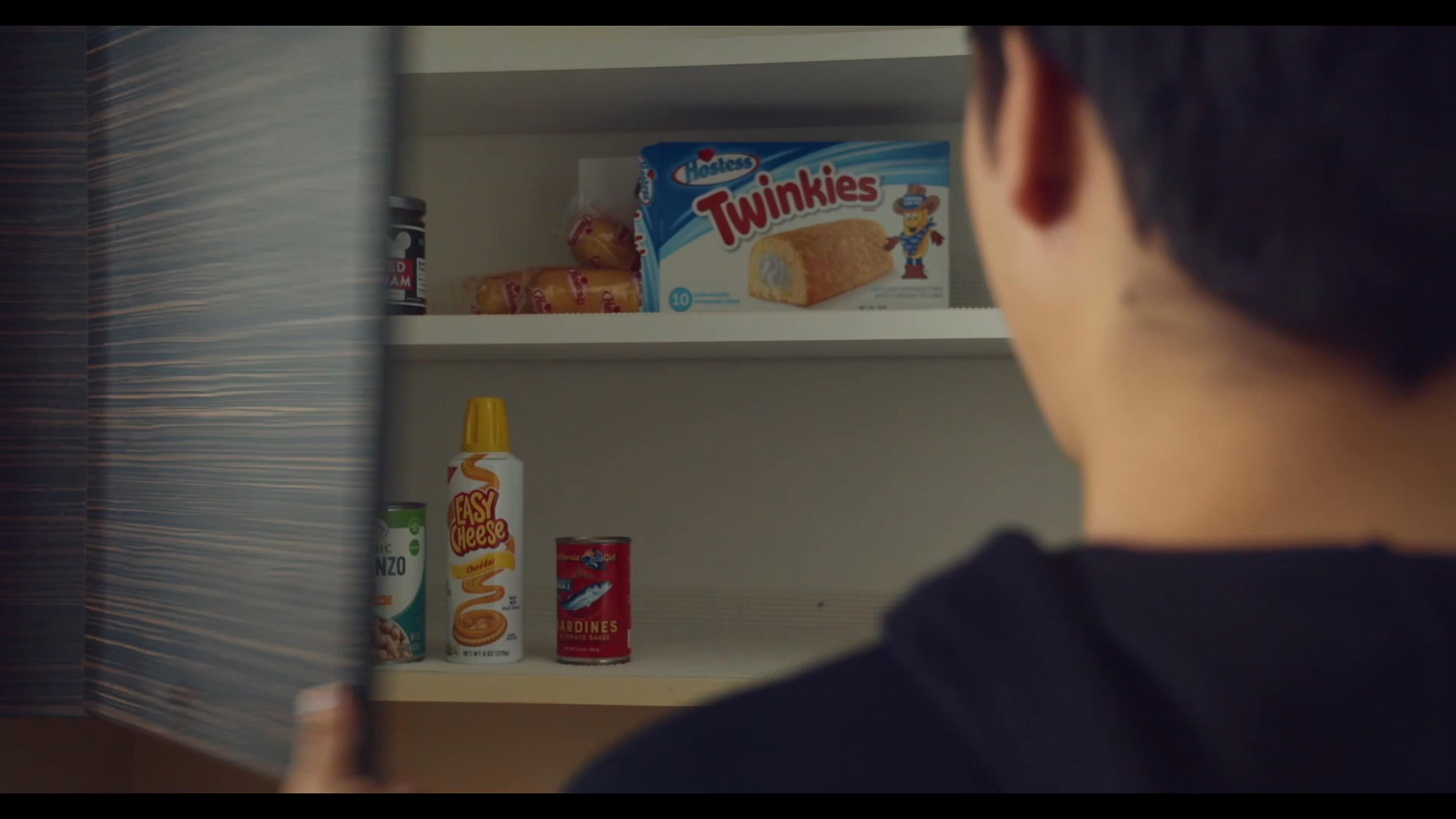 A man scavenges various snack items from his kitchen and combines them into a blender to create an experimental beverage.