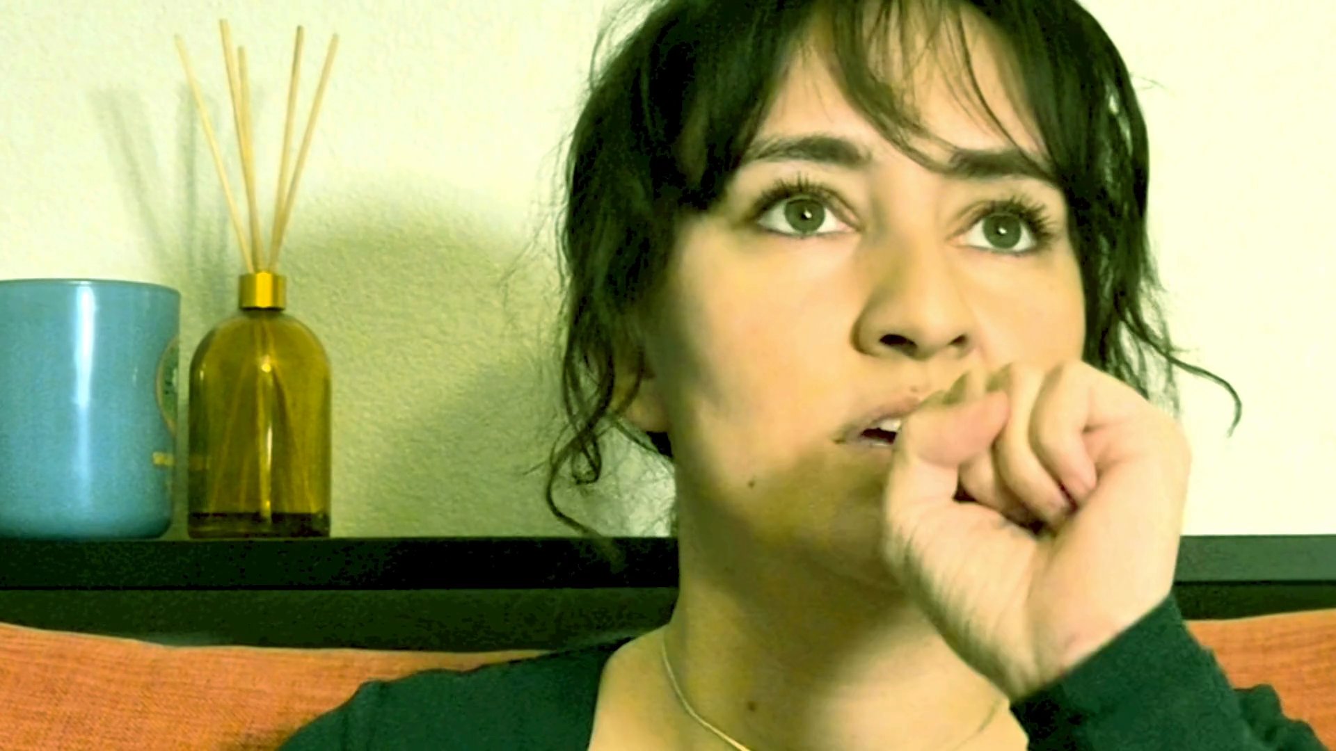 A woman performs a series of expressive gestures, miming the action of eating while looking directly at the camera.