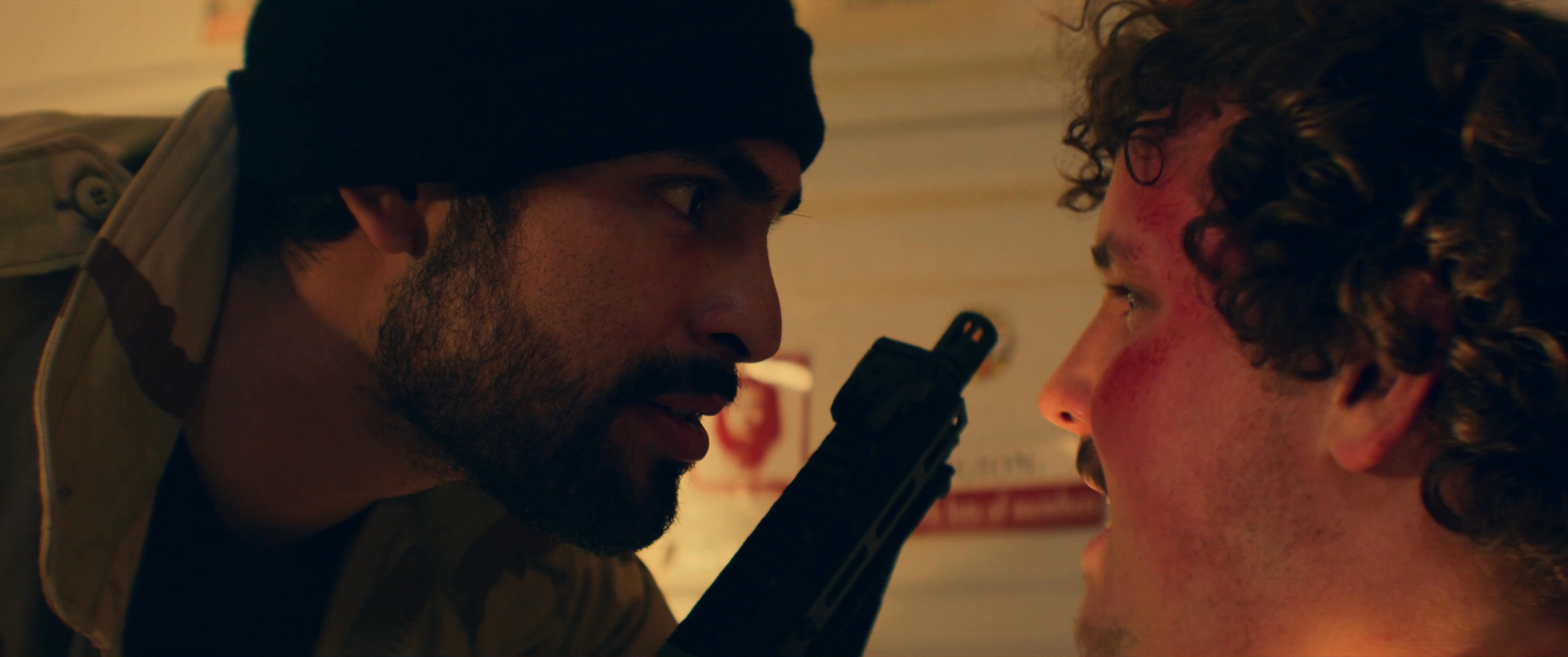 Two men engage in an intense, face-to-face confrontation inside a room decorated with political posters. The interaction is marked by palpable tension and verbal exchange.