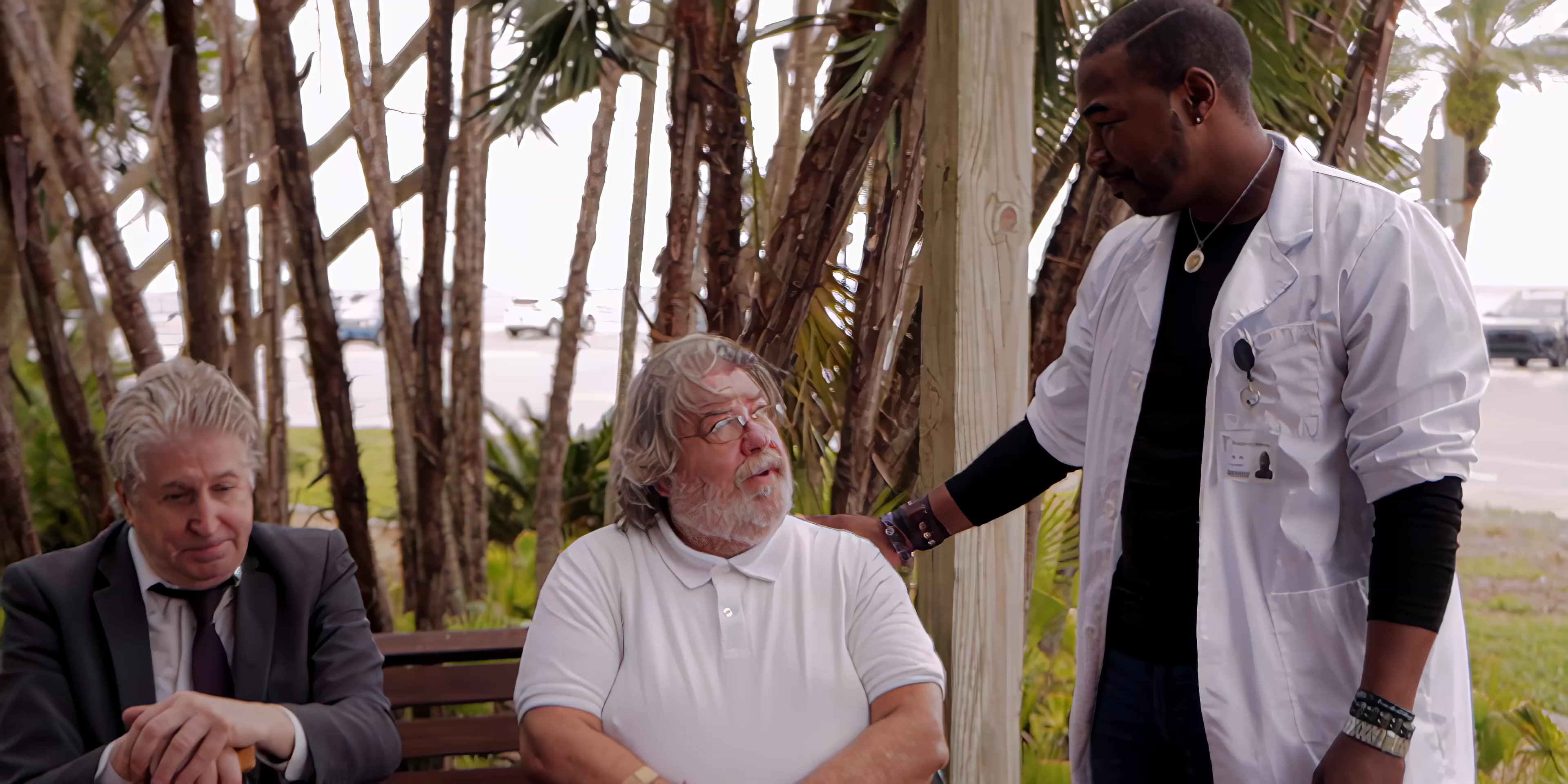 A professional in a lab coat provides guidance and support to two men seated on a park bench. The interaction involves a calm conversation focused on mentorship and interpersonal care.