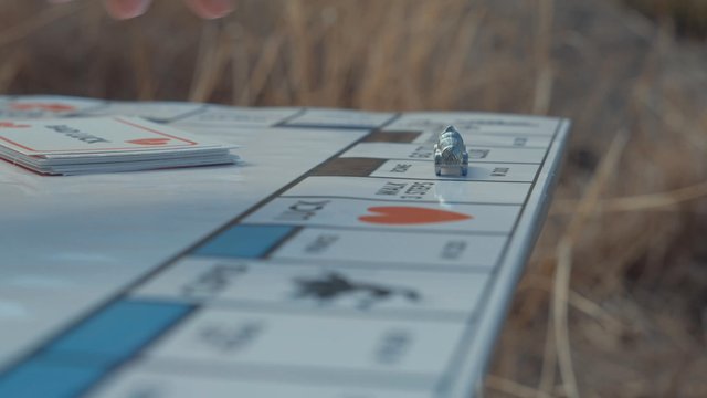 A guy moving his car piece while playing a board game