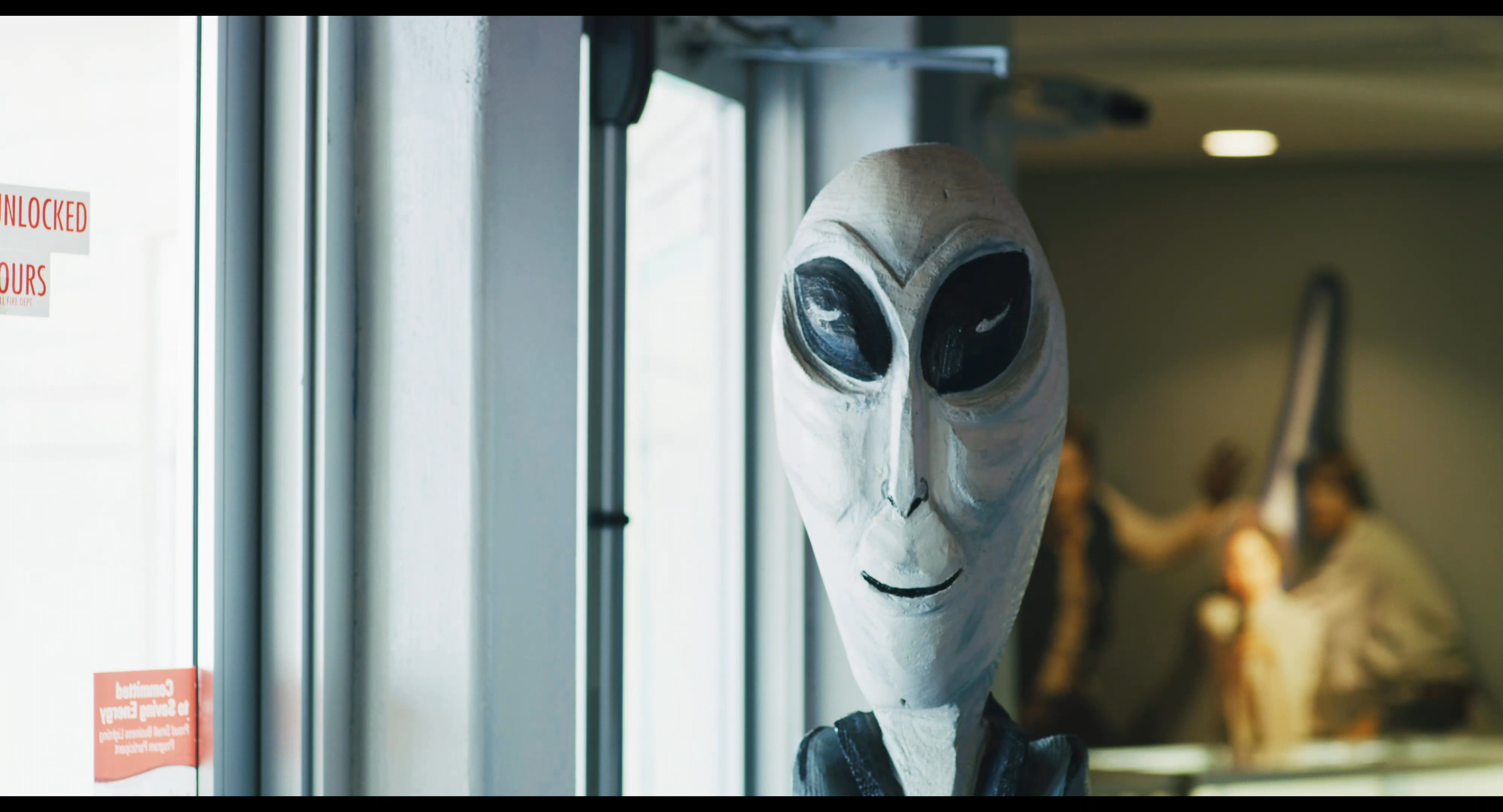 Two visitors walk into the Roswell UFO Museum and examine exhibits detailing the history of the 1947 incident, including alien models and event timelines.