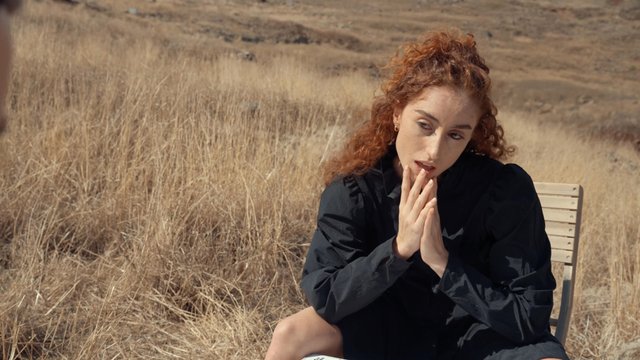 A girl singing by a table in a field of grass