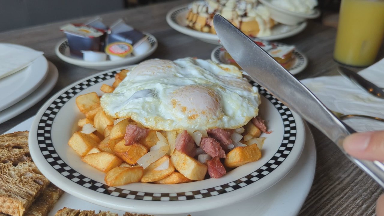 Rise & Dine Eatery - Cutting into over-easy eggs on the corner beef hash. - Breakfast & Brunch Near Me - Toronto, Ontario