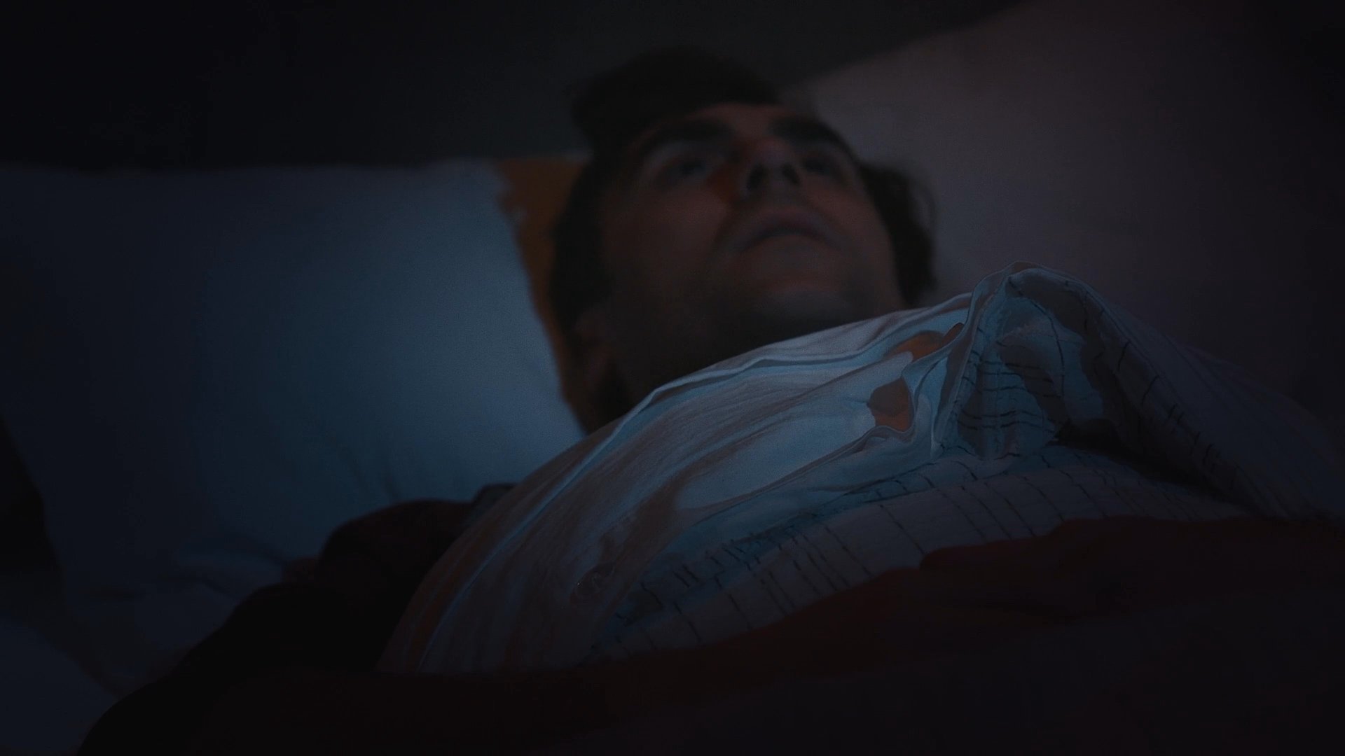 A woman prepares food in a kitchen before the scene transitions to a couple resting in bed and concludes with the woman walking through a bright modern living space.