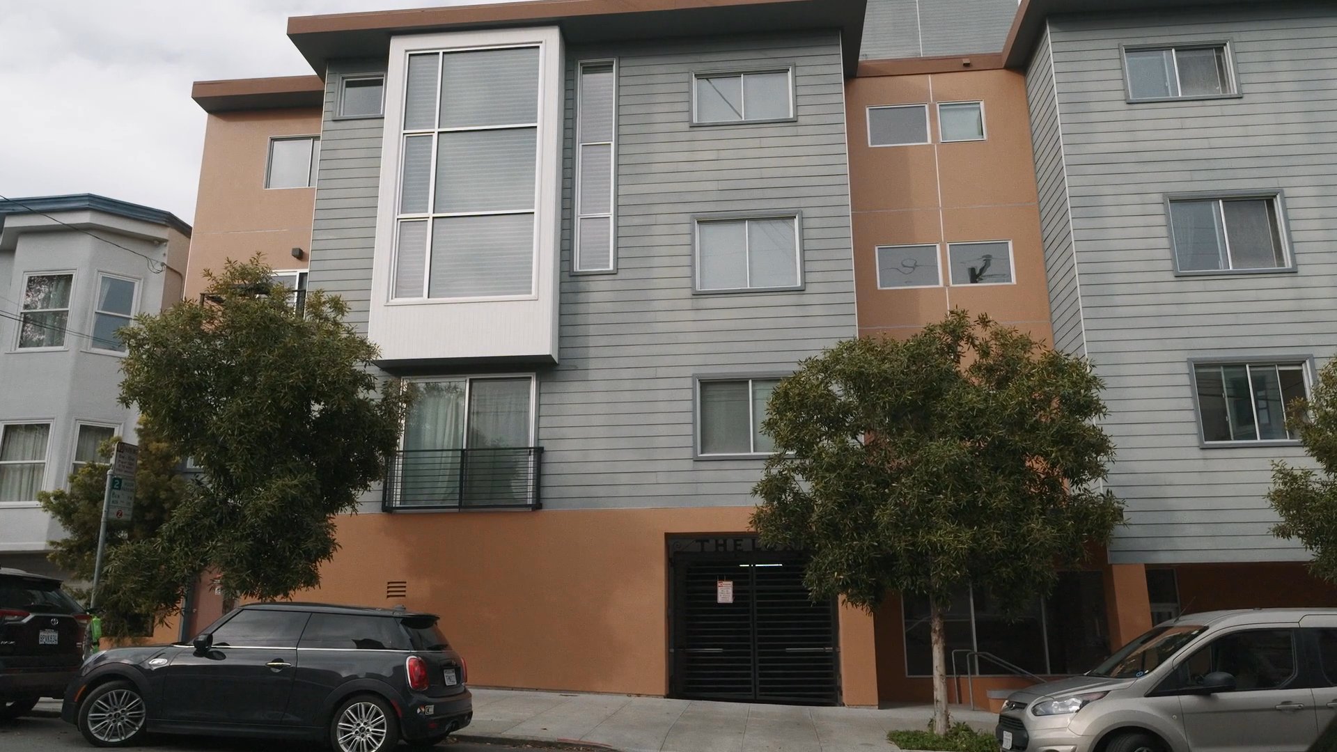 A person transitions from a dimly lit home interior to an exterior view of an apartment building before returning to a brightly lit, modern living space.