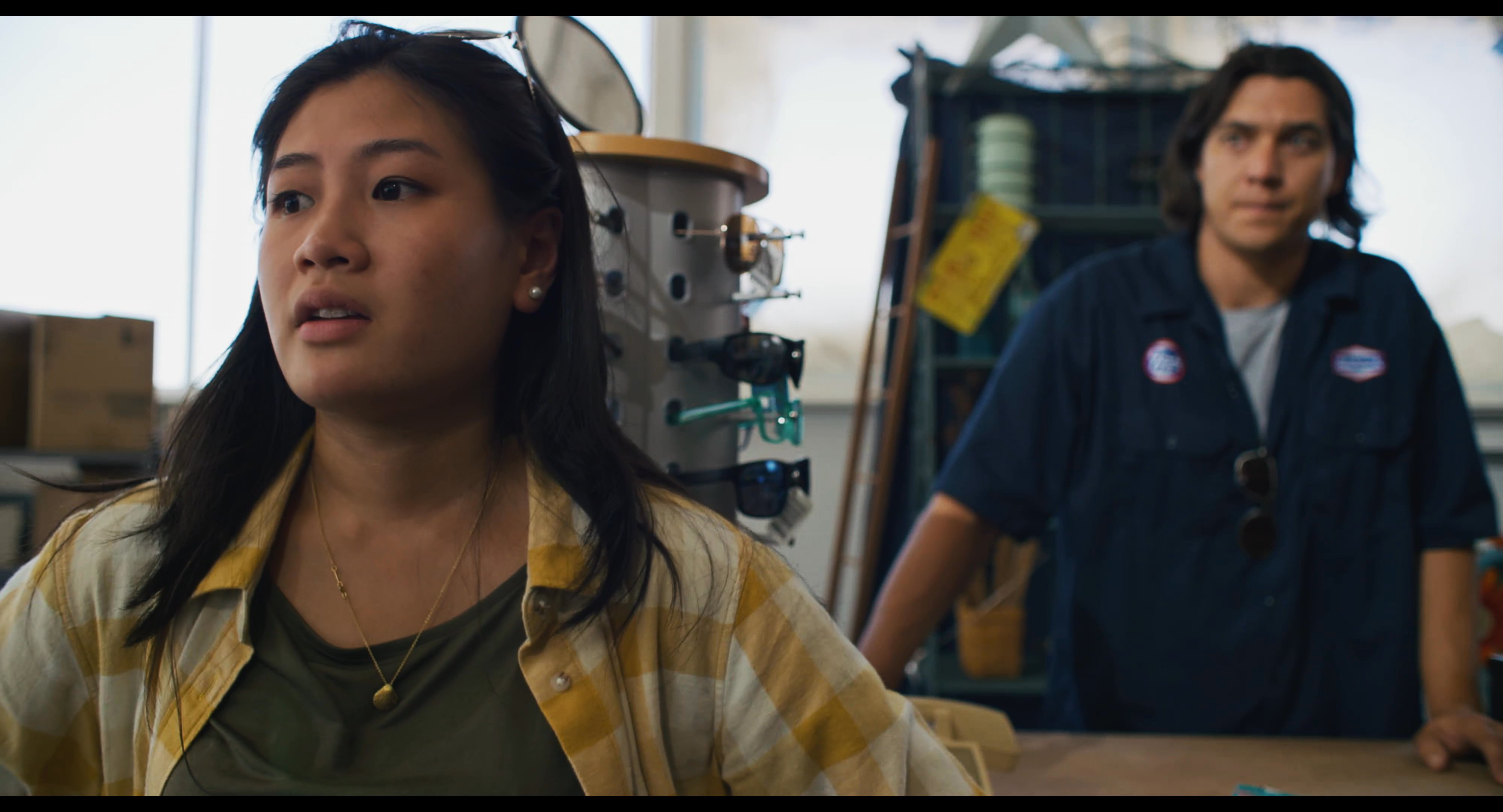 A woman appears visibly distressed while speaking to a retail employee at a service desk, eventually leaving the store to sit outside.