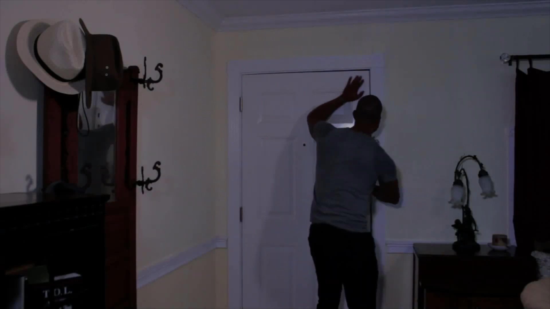 Two men engage in an intense, brief conversation before one man exits the house and the other secures the front door from the inside.