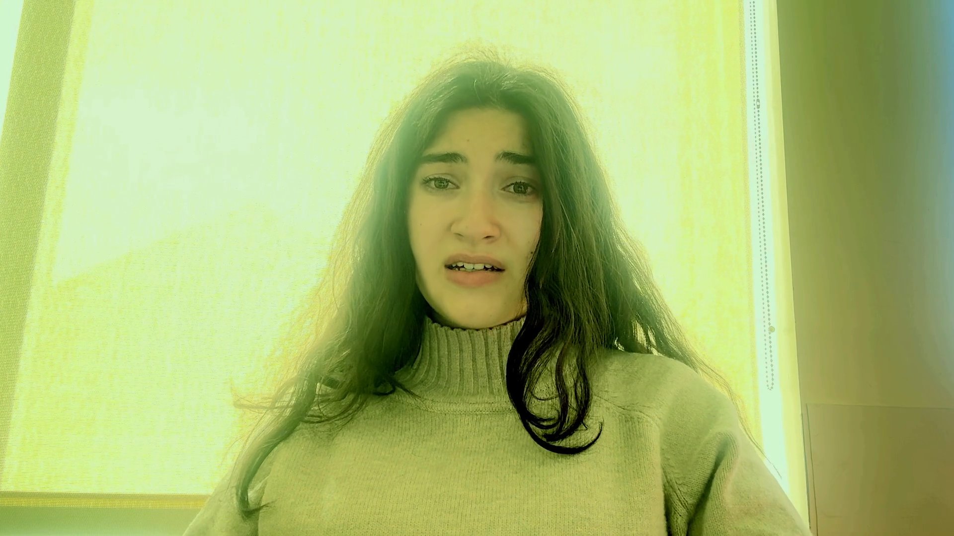 A woman performs an expressive vocal song in a bright, indoor setting. The focus remains on her emotive delivery and facial expressions throughout the musical piece.