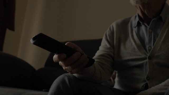 Old man switching between channels using a remote control