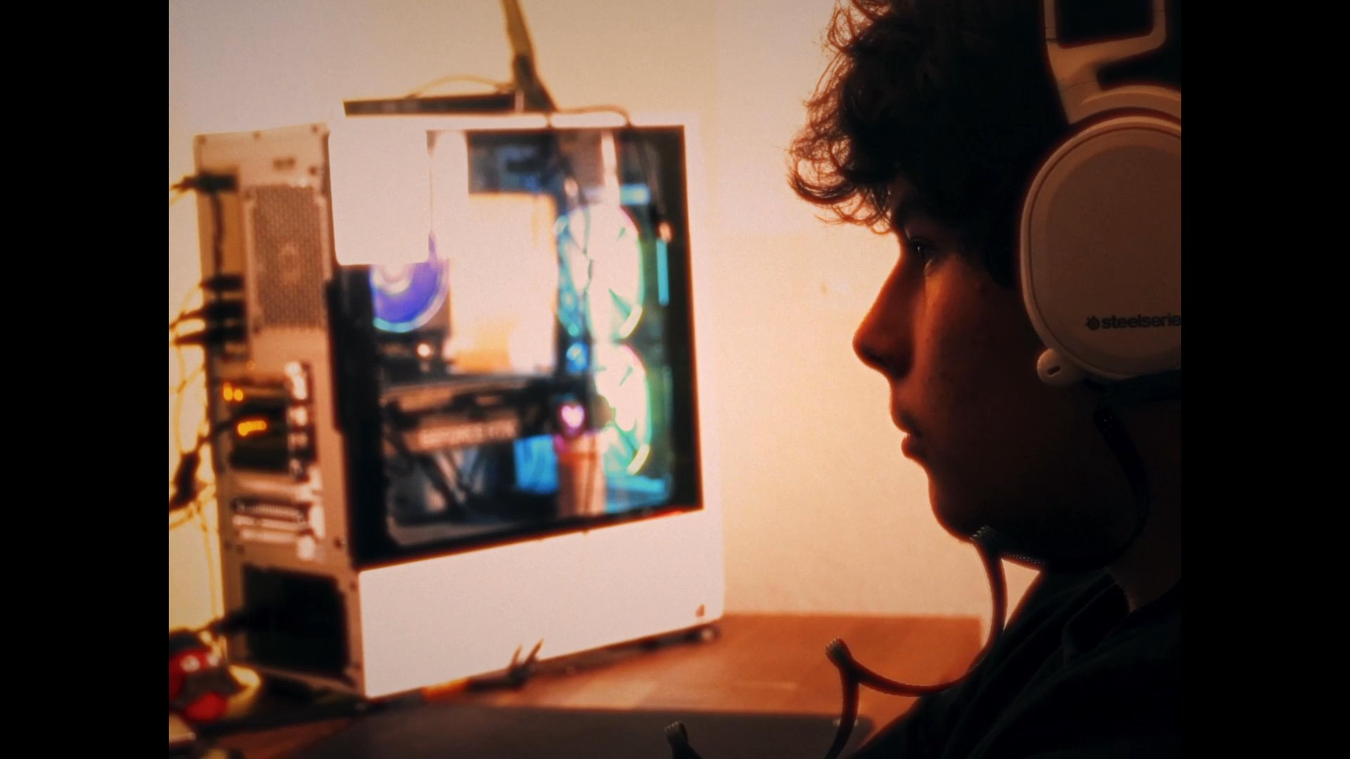 A young individual wearing a headset engages with a computer interface featuring a loading network sequence and a note documenting the objective to make a friend.