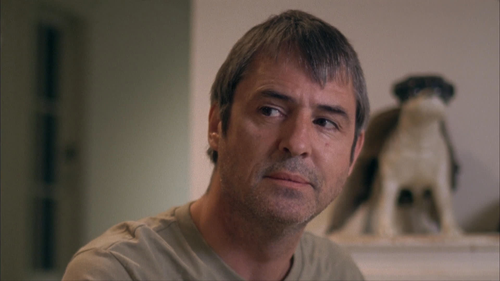 Two men engage in an informal, focused dialogue within an interior setting, alternating between listening and speaking while maintaining intermittent eye contact.