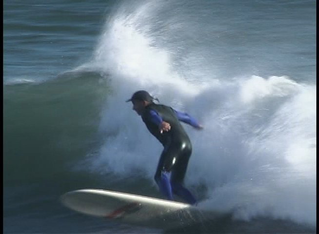 A coach provides expert instruction on surfing technique while a surfer demonstrates skills by riding waves in the ocean.