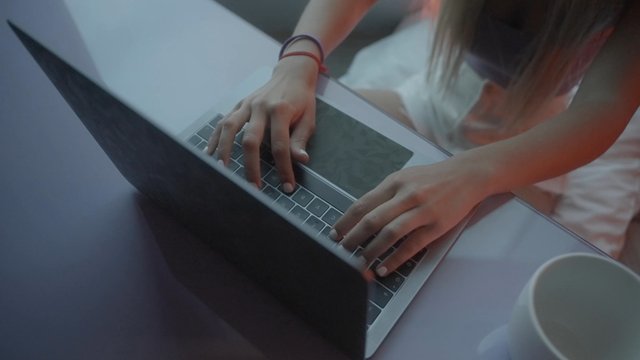 A girl sitting at her desk and typing on her laptop