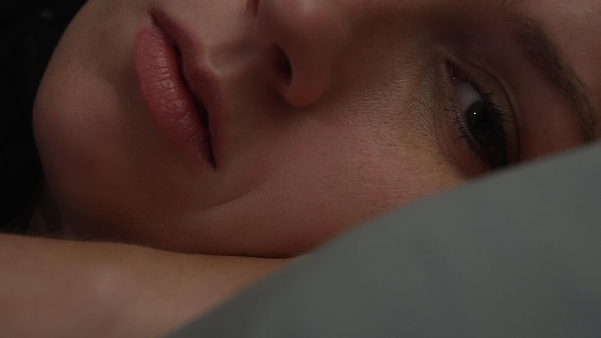 A transition occurs from a lively evening social gathering to the following morning in a bedroom where a woman wakes up and prepares for the day while her partner remains asleep.