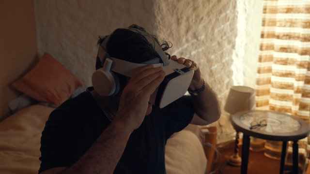 An adult man putting his VR goggles on on his face
