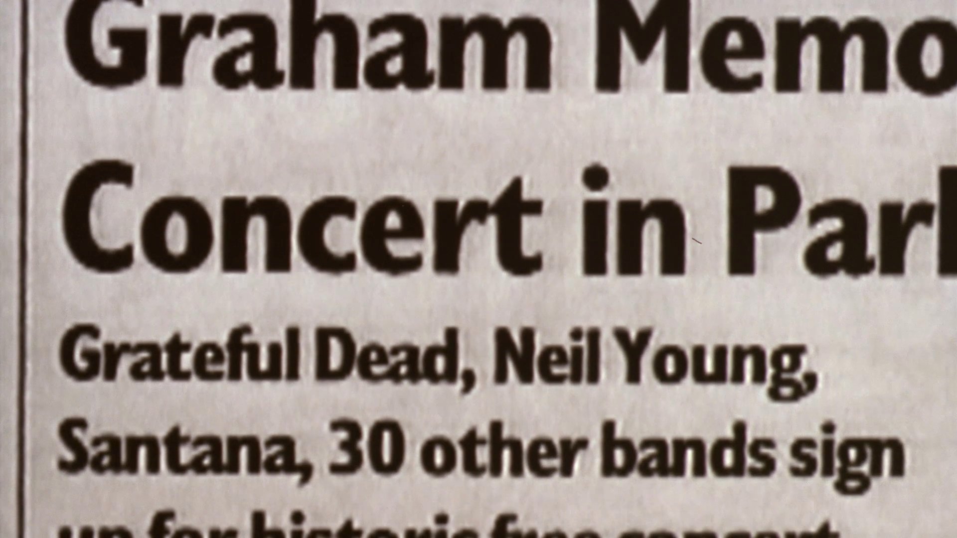Archival newspaper headlines report on the announcement of a large-scale memorial concert in the park, followed by scenes of live musical performances before a massive audience.