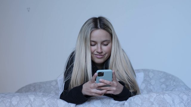 Girl using iPhone in bed