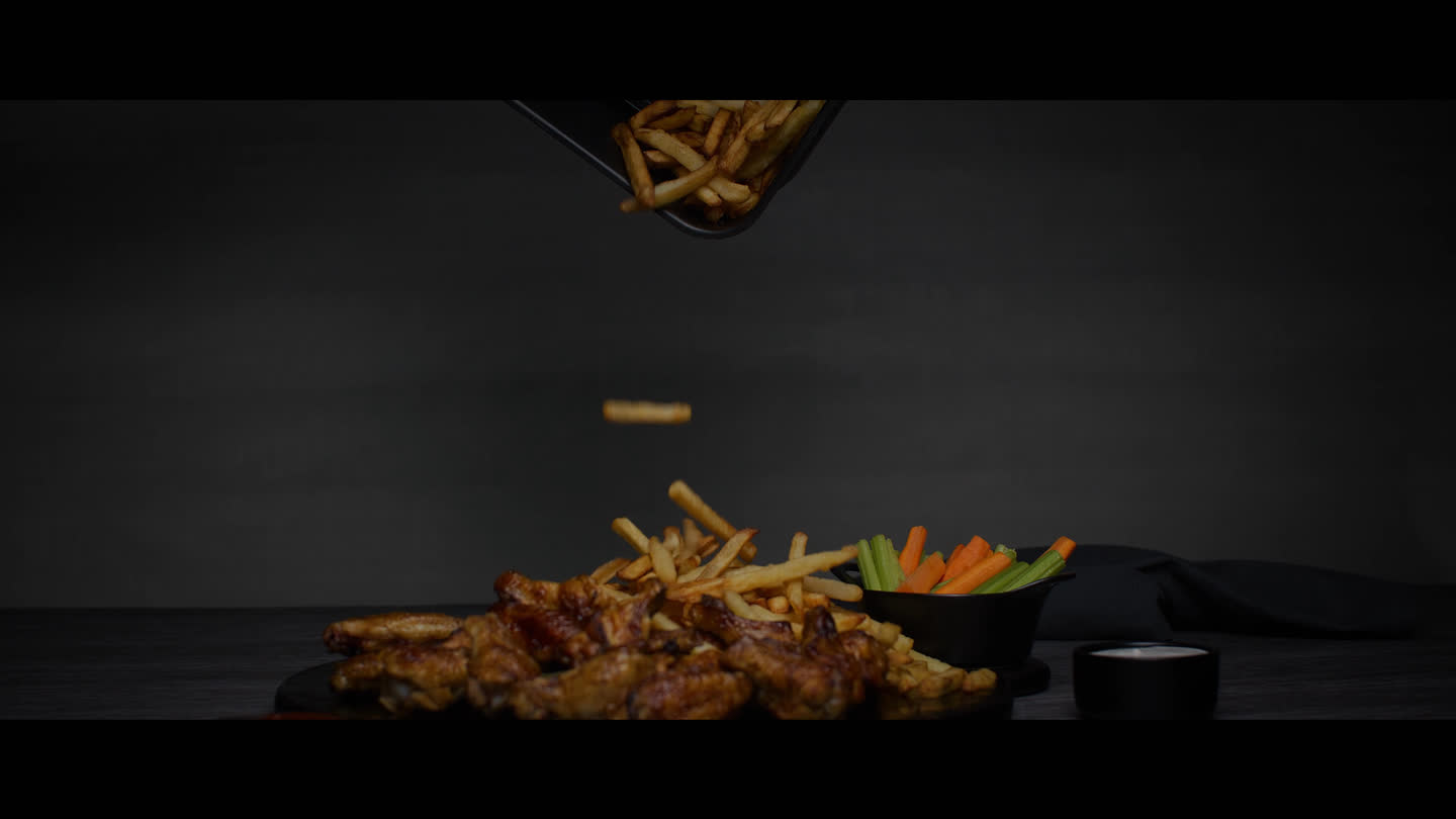 Film still: fries falling from an air fryer basket onto a plate