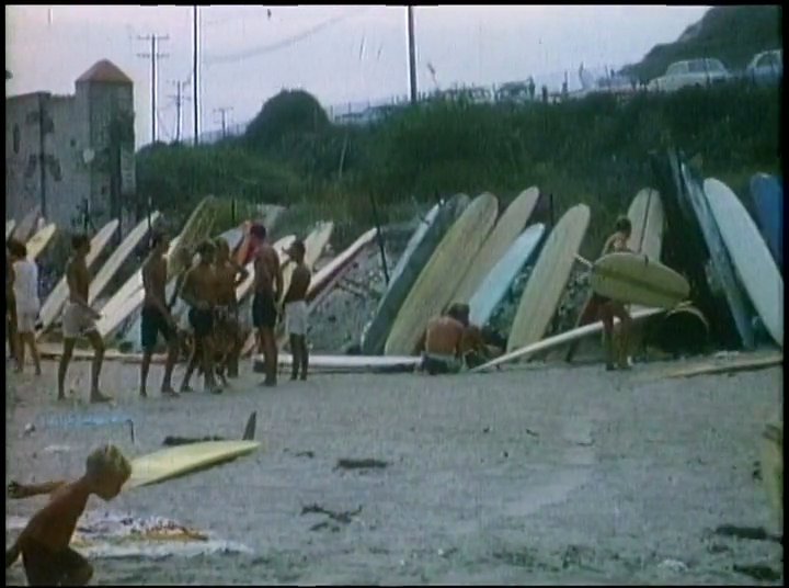 Surfers congregate on a sunny beach lined with numerous surfboards, capturing the mid-century coastal lifestyle. The sequence culminates in visual references to The Beach Boys' musical legacy.