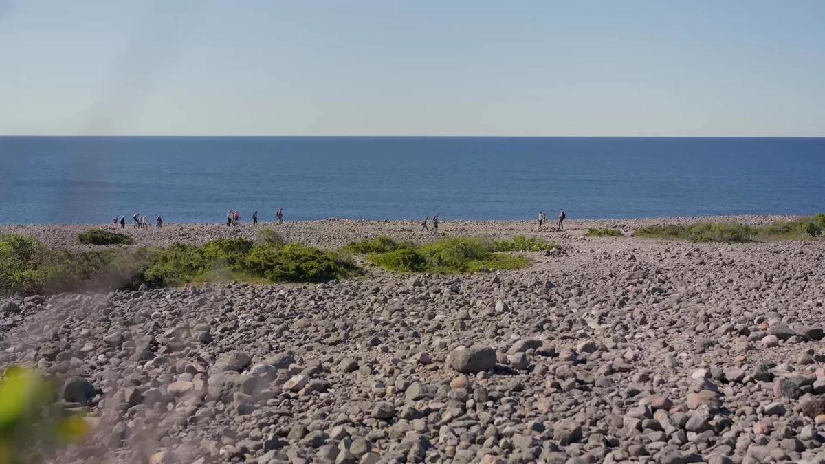 People walking on a stone beach.