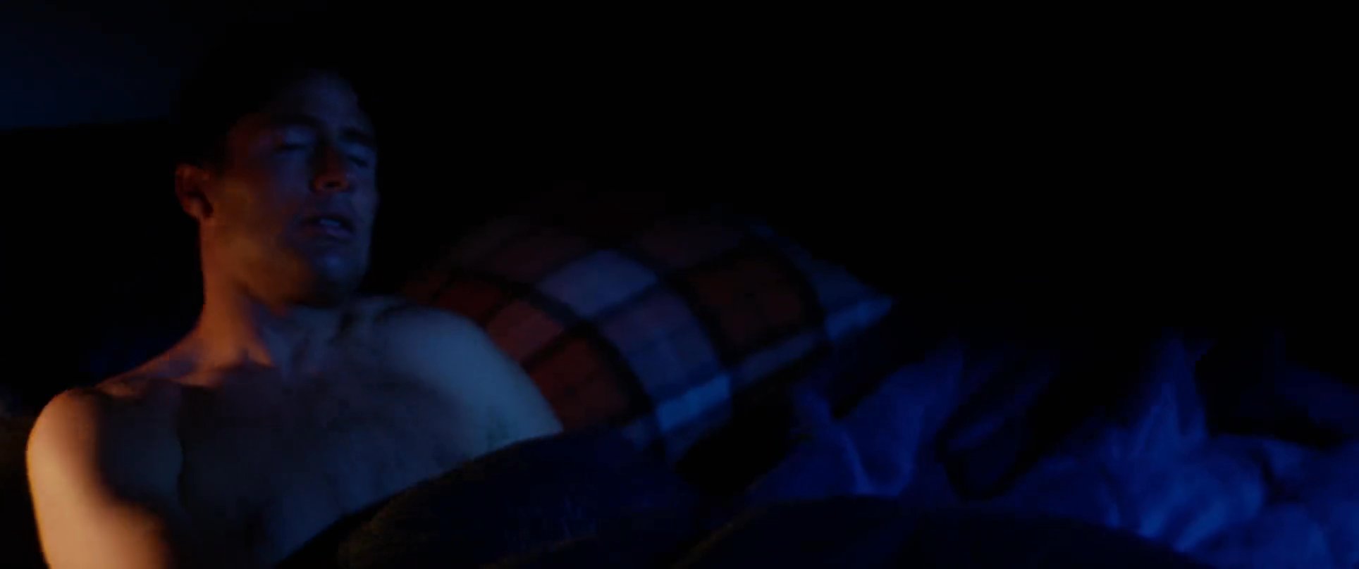 A man wakes up in a darkened room, appearing distressed or pensive, before the scene transitions to an aerial view of a rugged coastline and the Ghost Trees location.