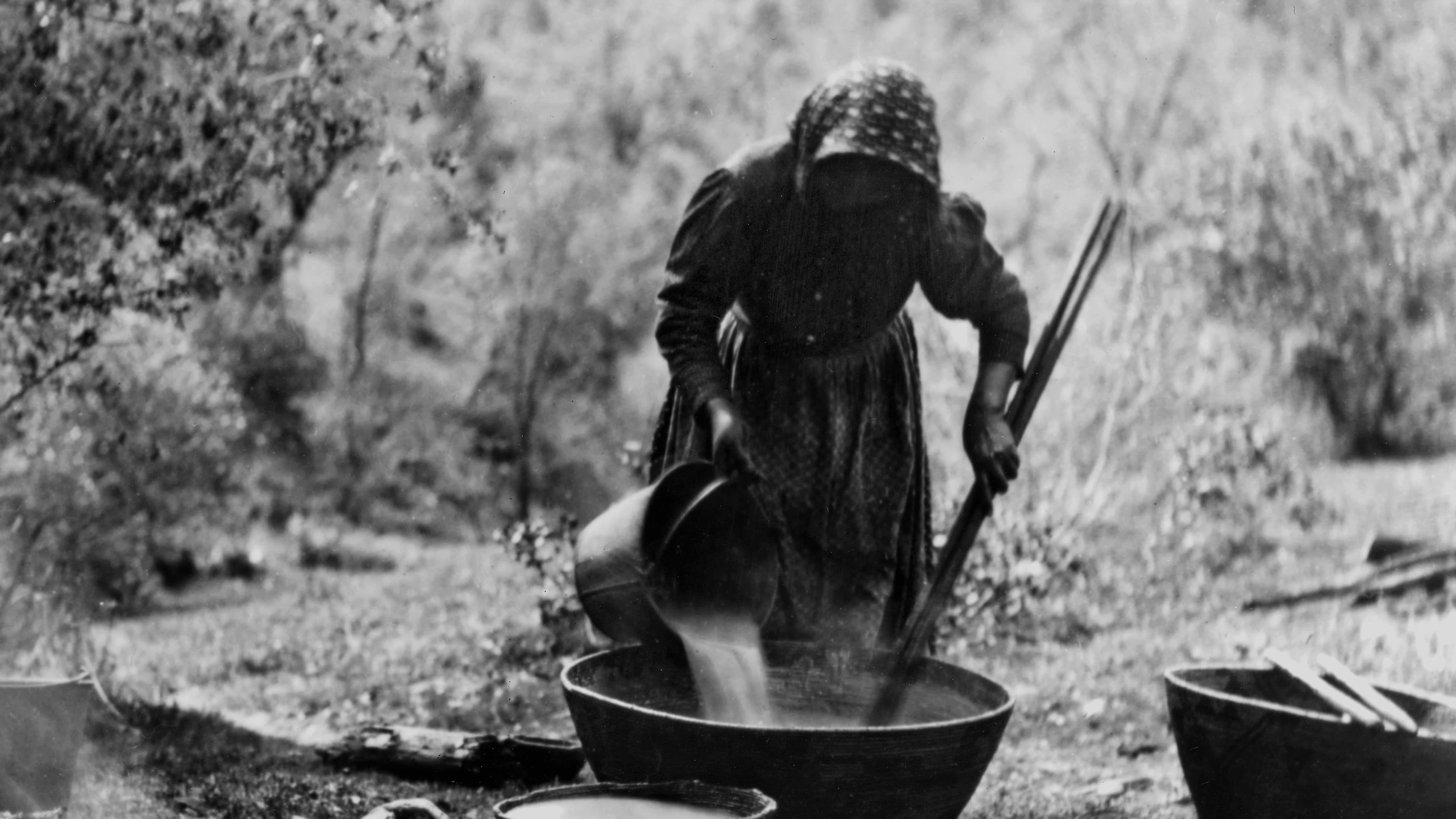 Archival photographs of women carrying baskets and working over a basin transition to a forested river landscape. Narration describes how the Gold Rush, genocide, enslavement, and restrictive laws disrupted Indigenous land-care knowledge, leaving landscapes untended for generations.