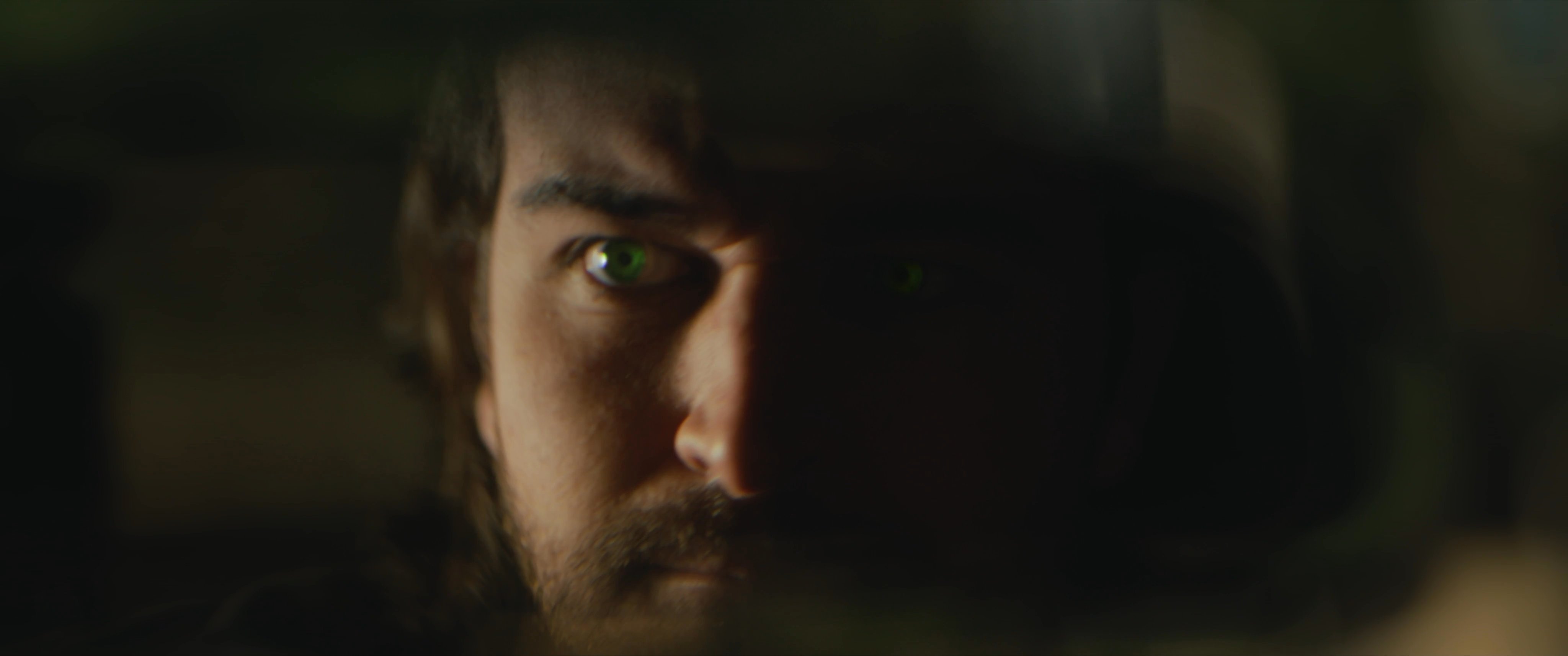 A man driving through a forest experiences a physical transformation as his eyes begin to glow, signaling a shift in his state or nature.
