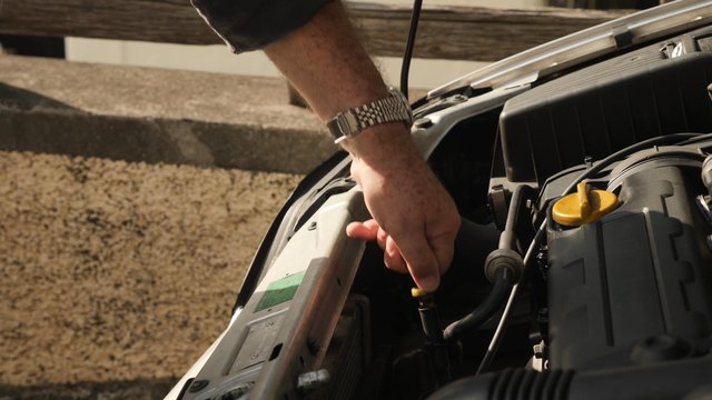 Man checks the oil level of a car