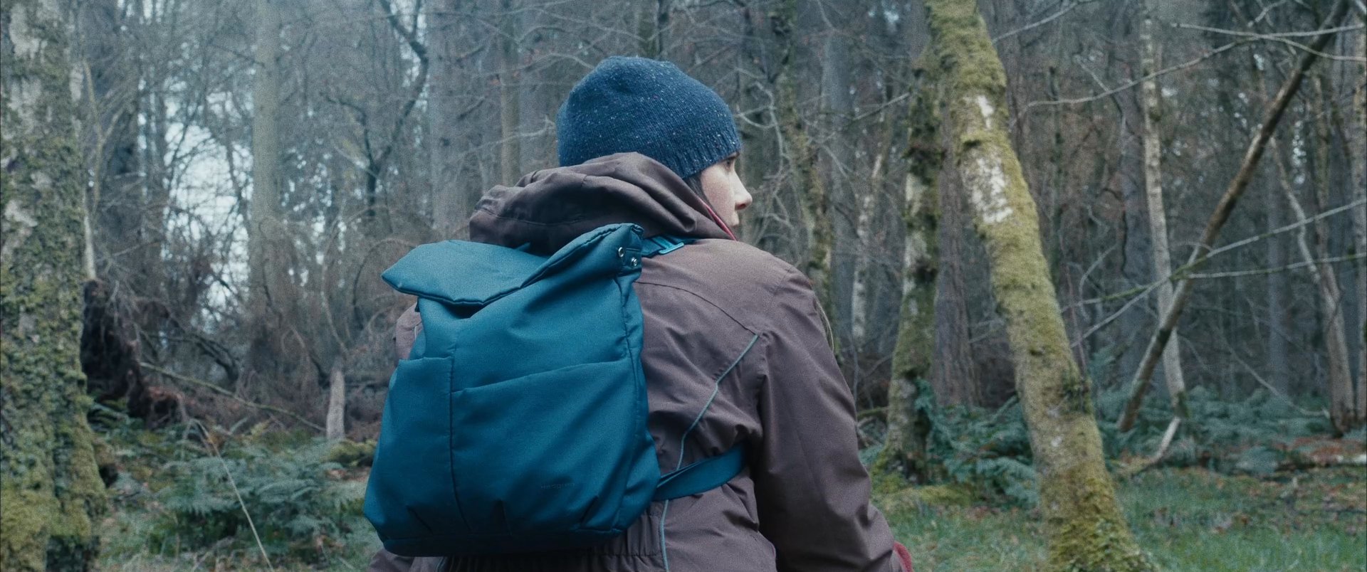 A hiker navigates through a dense, misty forest while checking a mobile device to verify location or progress.