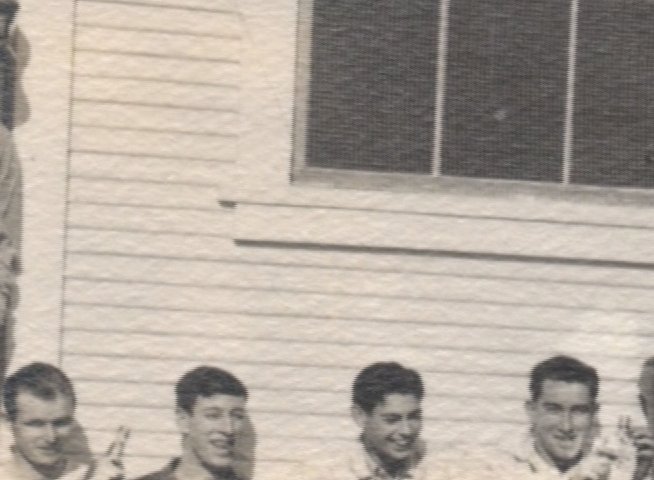An elderly veteran observes a vintage photograph of himself and his fellow service members. The narrative transitions between his present-day reflection and the historical image capturing a camaraderie-filled moment from his time in the navy.