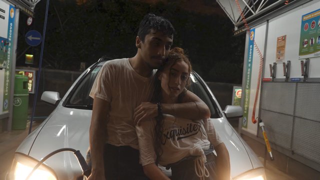 Hugging couple leaning on car