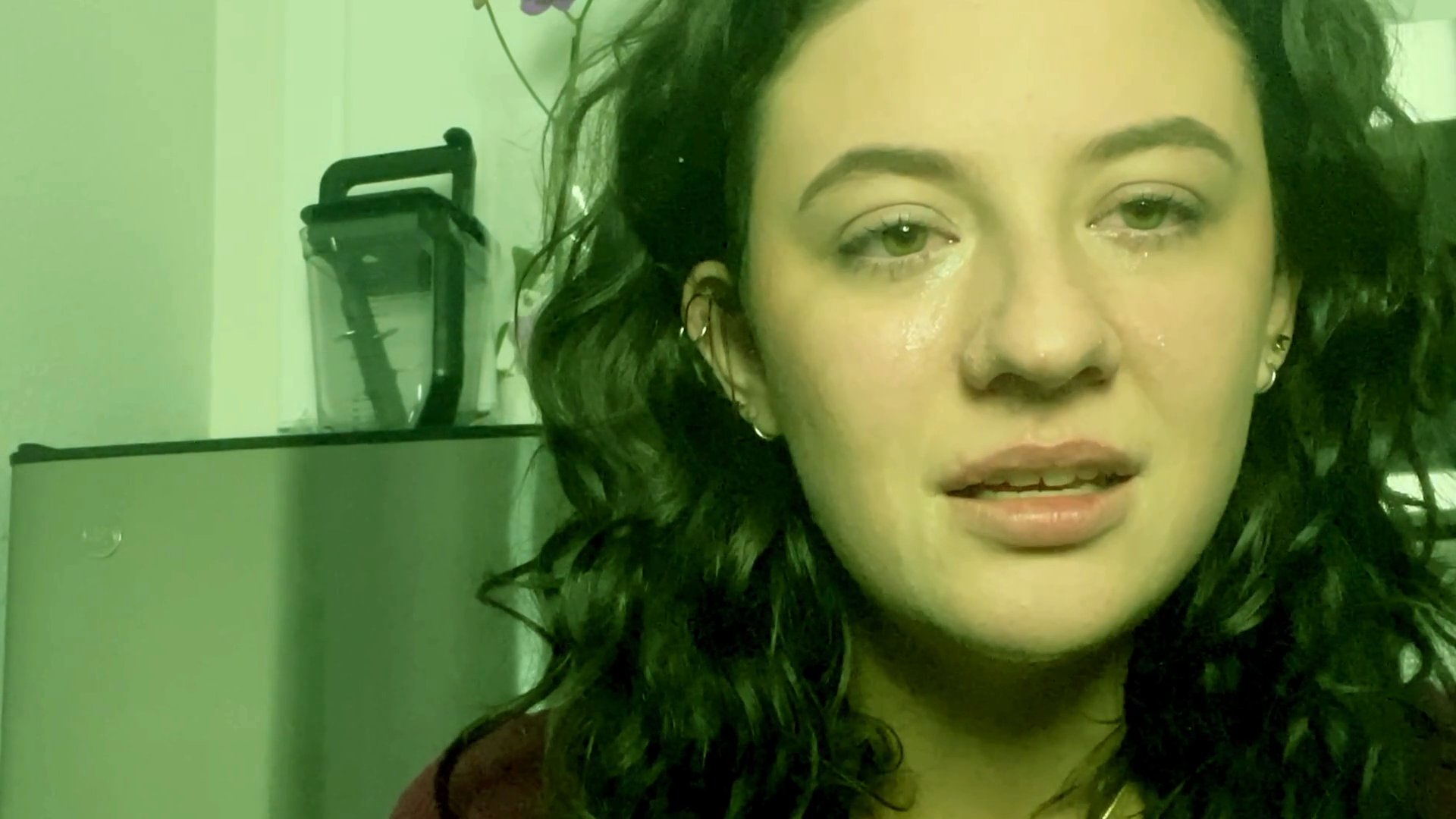 A young woman shares a candid, emotionally vulnerable moment while speaking directly to the camera. Her expression conveys deep sadness and sincerity during this reflective sequence.