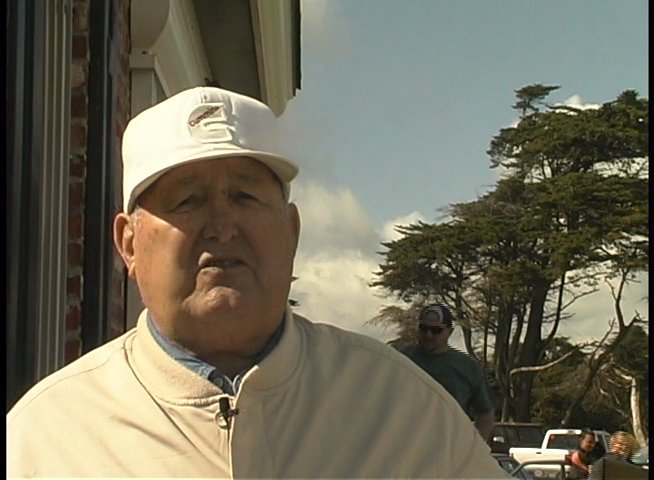 A man wearing a baseball cap speaks directly to the camera while gesturing outdoors, providing an account of his experience in a professional context.