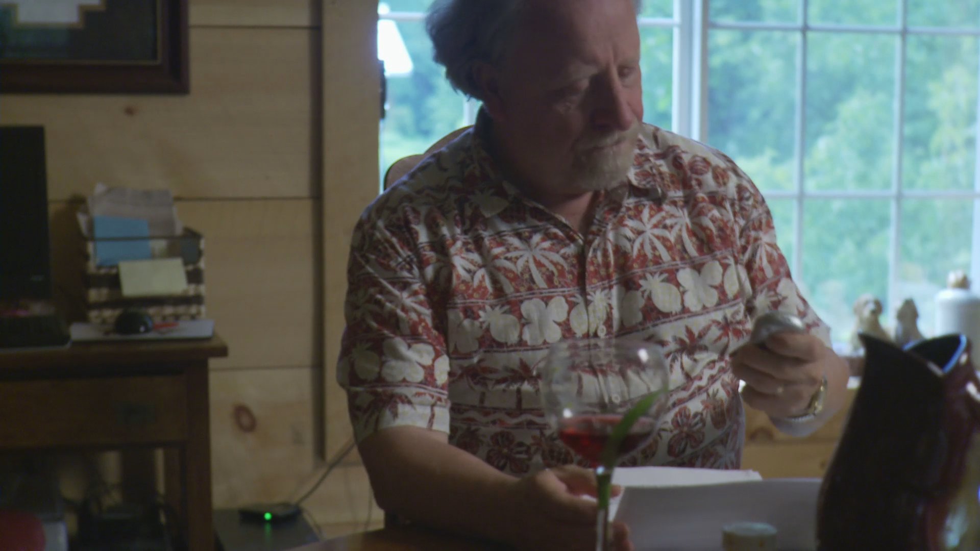 A man sits at a table reviewing documents before the scene transitions to a woman practicing tennis strokes and engaging in a phone conversation.