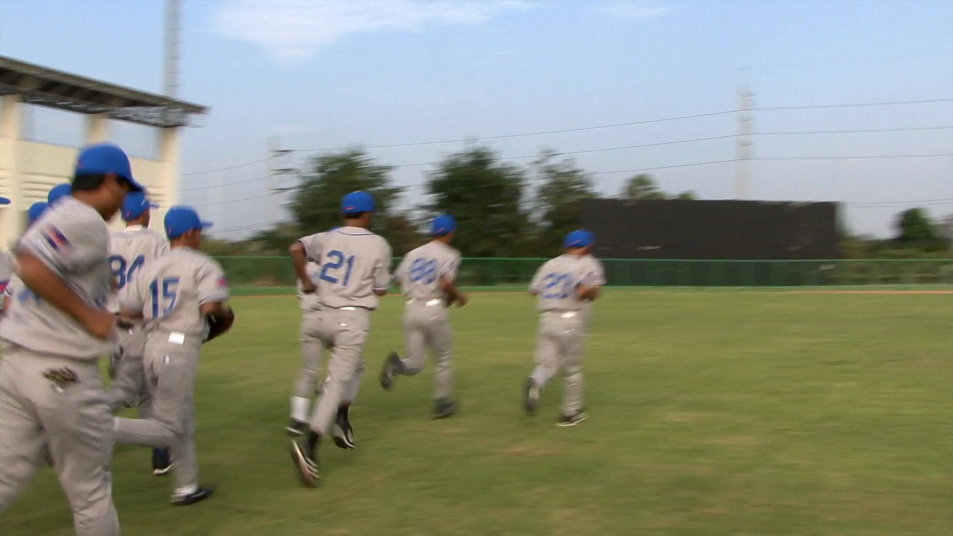 Members of the Cambodia national baseball team provide personal introductions before conducting physical training drills on a baseball field under the guidance of their coach.