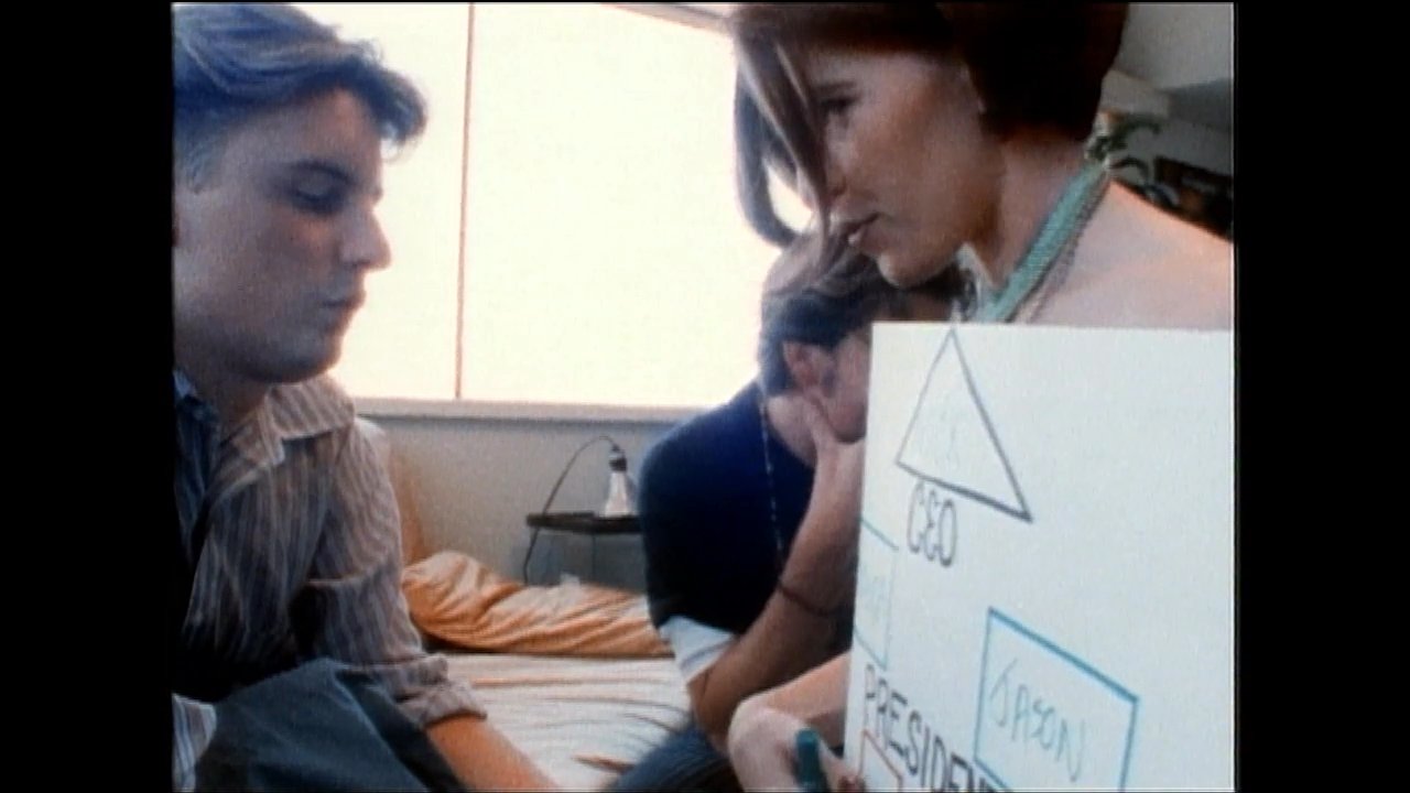 Three individuals review and discuss a hierarchical organizational chart during a professional meeting. The group evaluates team structure and leadership roles while documenting the company's internal composition.