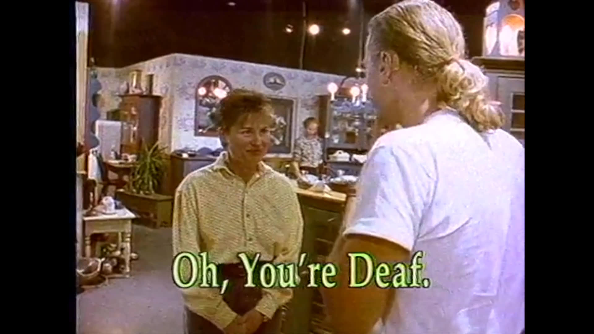 A retail store employee interacts with a deaf customer who uses sign language to communicate, leading to a moment of mutual understanding and accommodation.