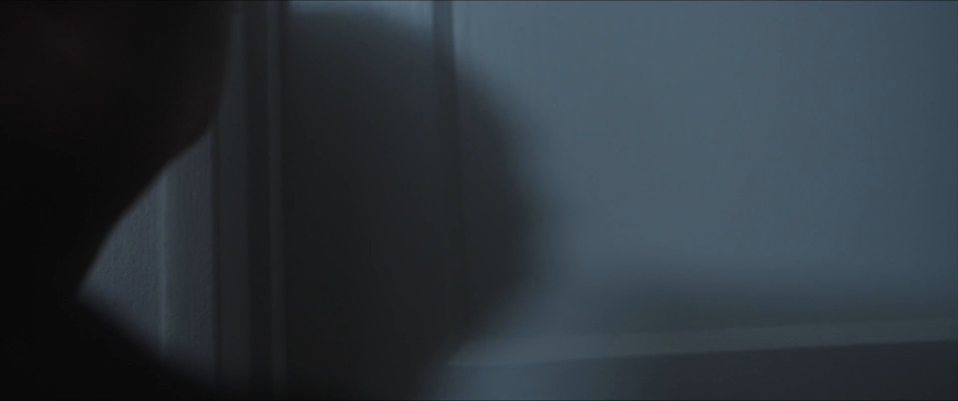 A man engages in a personal grooming routine in a bathroom before a visitor knocks on the door and greets him.