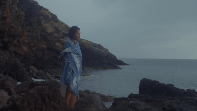 A girl wrapped her in a towel standing on the beach
