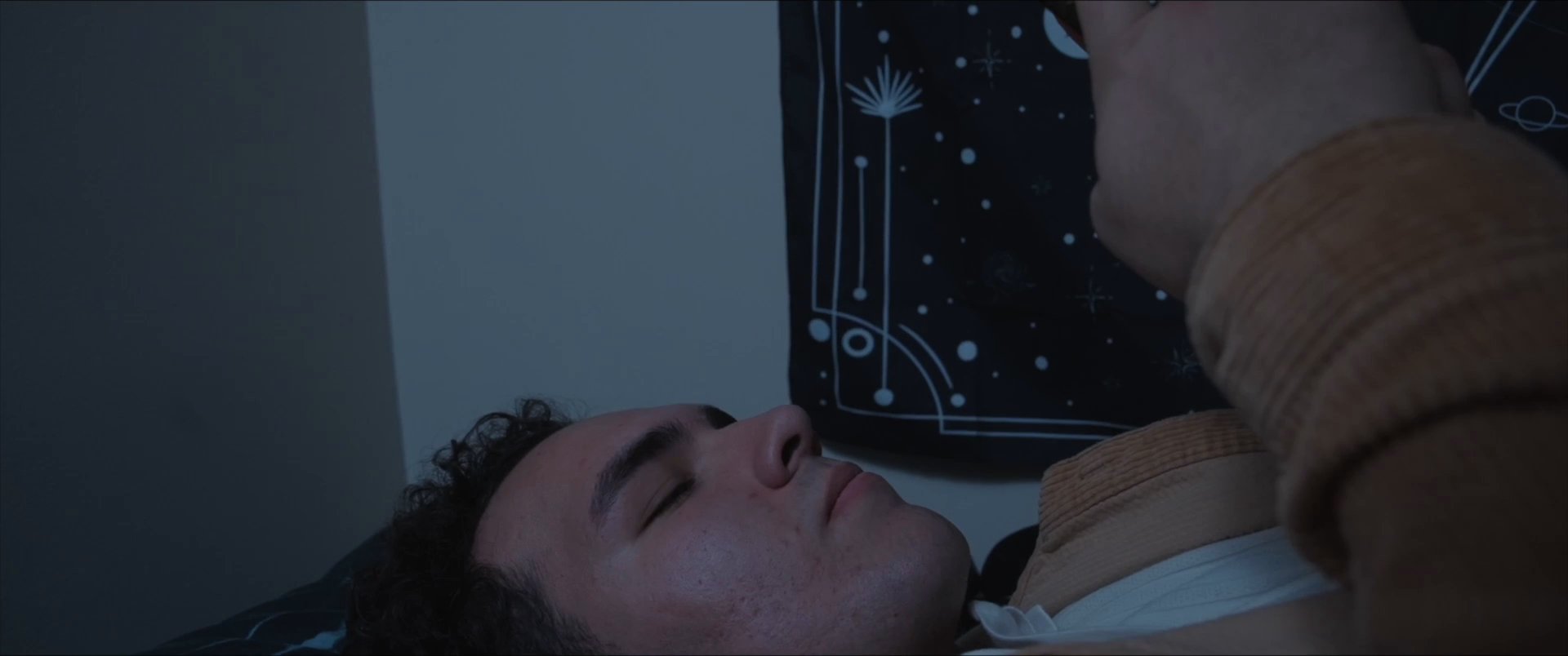 An individual lying in a dimly lit room uses a smartphone to exchange social media messages regarding a planned surprise birthday celebration.