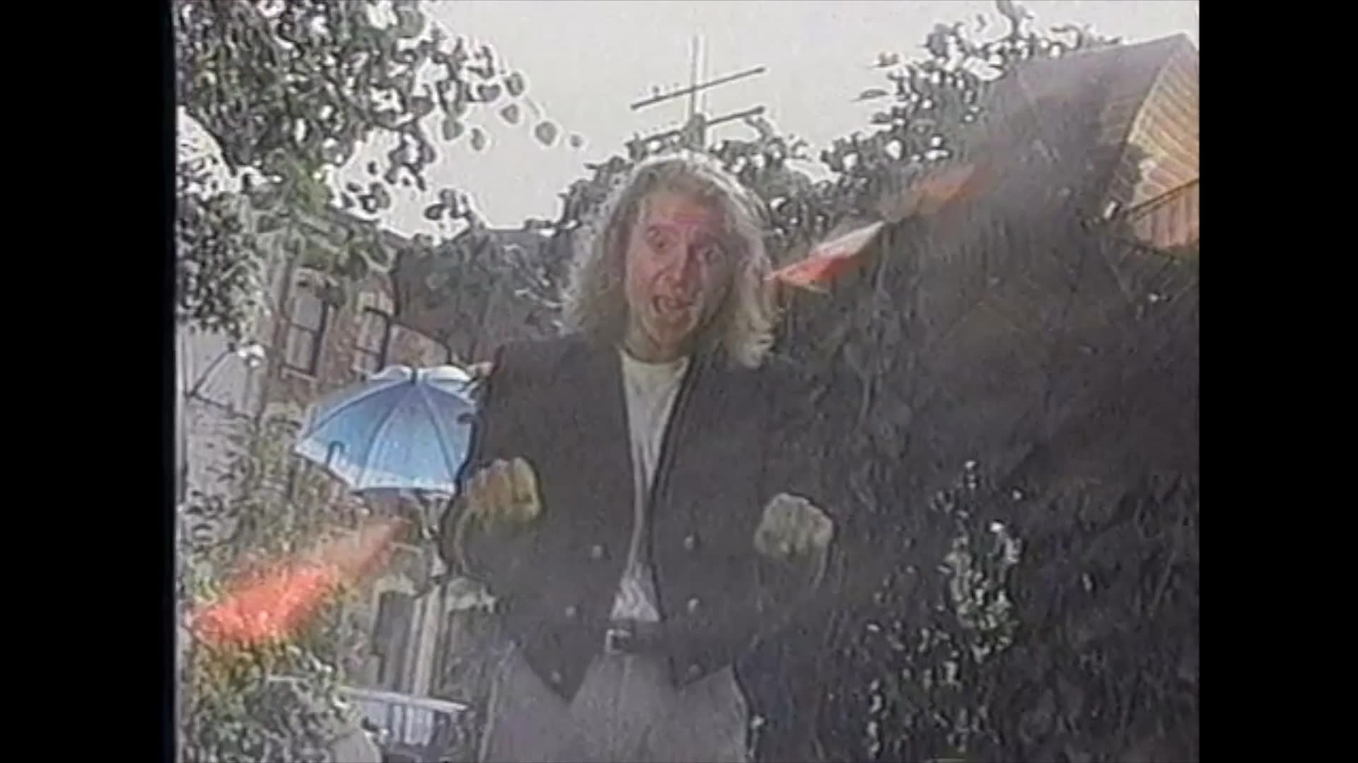 A long-haired magician performs a sequence of hand gestures and card tricks outdoors, providing verbal prompts to guide the viewer through each step of the routine.