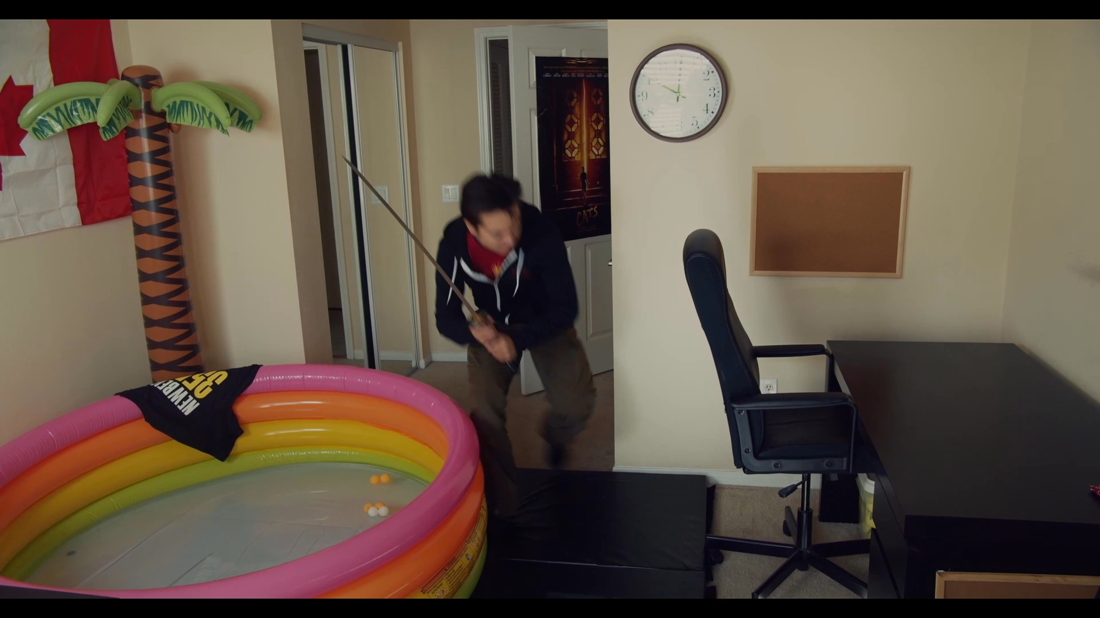 A man engages in a choreographed sword fight using a katana within a residential apartment setting. He moves through various rooms, demonstrating defensive maneuvers and tactical positioning.