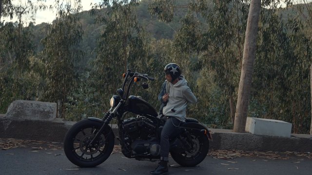 A motorcyclist putting on a woolen jacket