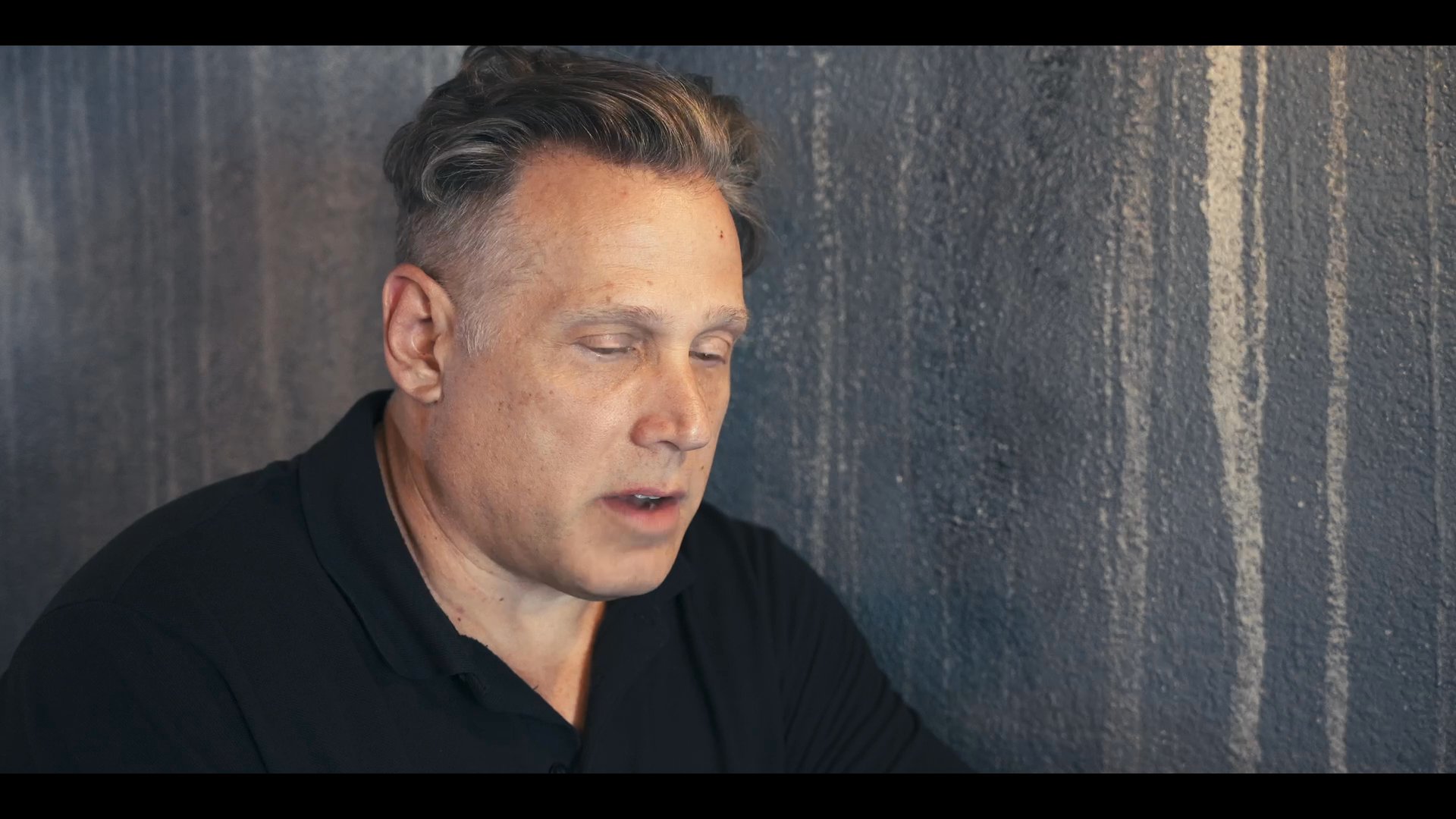 Two individuals engage in a focused, seated conversation, exchanging ideas against a textured backdrop. The scene highlights interpersonal communication and professional collaboration.