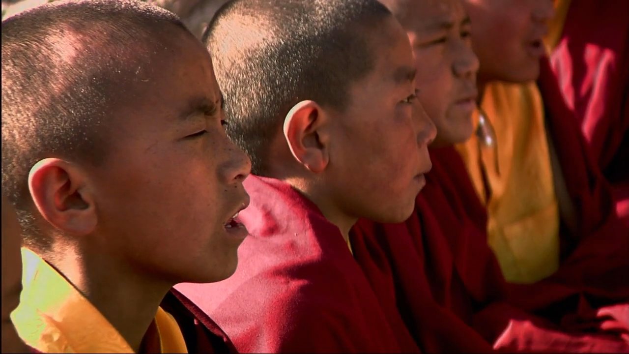 Monk Tashi Tenzing discusses life at Choedhe Monastery as young novices engage in traditional chanting and prayer within the temple grounds.