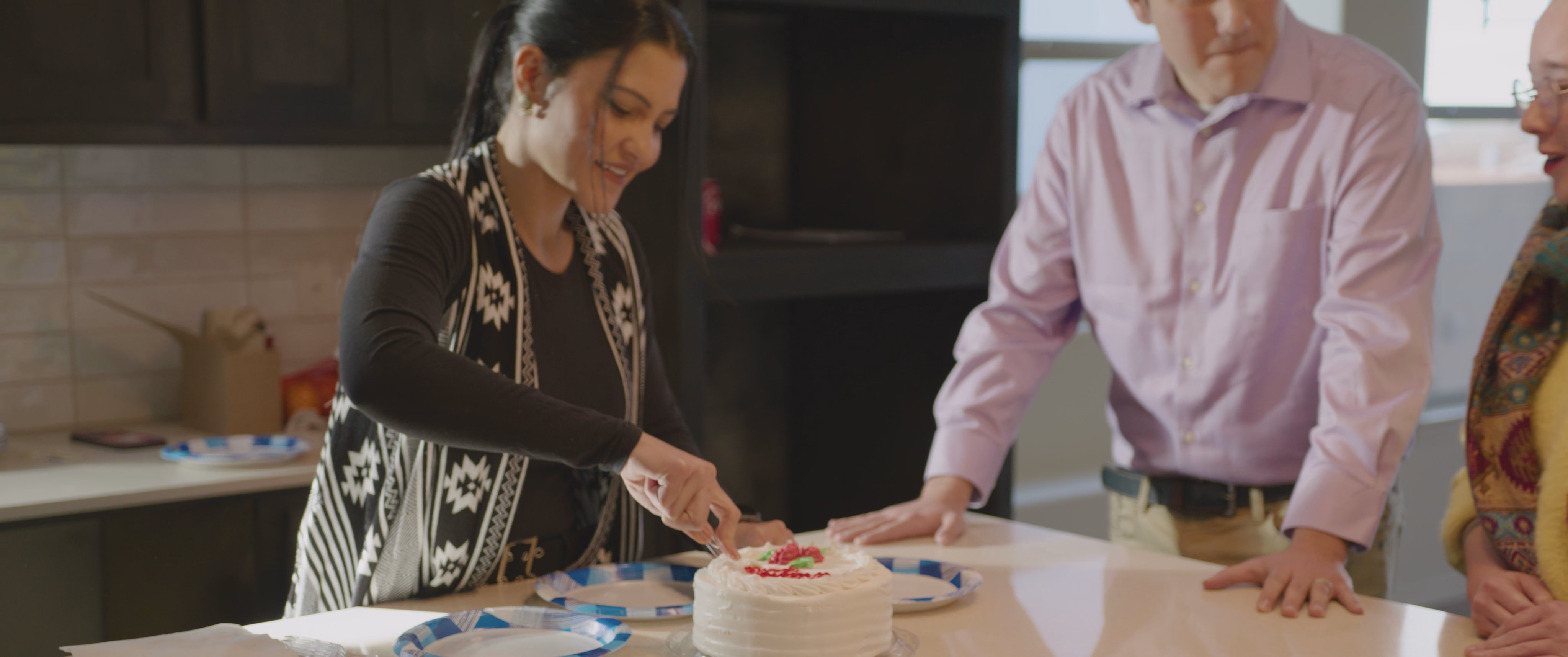 Individuals conduct a final inspection of a new residential construction project before transitioning to an indoor gathering to celebrate with a cake-cutting ceremony.