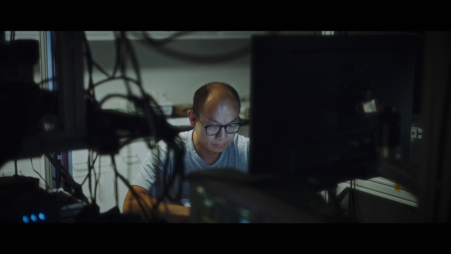 Film still: a team member concentrating on a computer in Xanadu’s laboratory